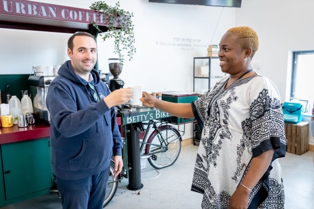 Person serving a customer a hot drink in a café as part of hospitality barista skills training.